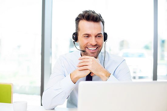 Man with headset looks into notebook with smile.